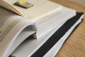 pile of books open with post it and folder on top